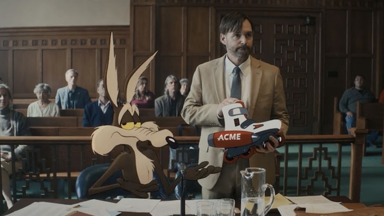 Wile E. Coyote stând lângă Will Forte ca Kevin Avery într-o sală de judecată în Coyote vs. Acme