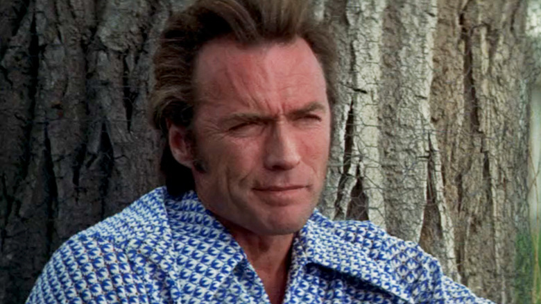 Thunderbolt al lui Clint Eastwood se uită în depărtare în timp ce se sprijină de un copac în Thunderbolt și Lightfoot