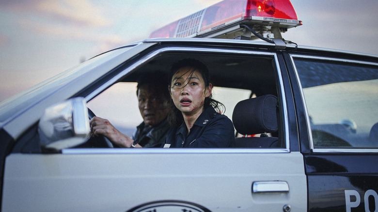 Hoyeon ca Sung-ae conducând o mașină de poliție lângă Hwang Jung-min ca Bum-seok în Hope