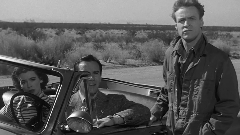 Ellen Fields din Barbara Rush și John Putnam din Richard Carlson stau într-o mașină în timp ce George al lui Russell Johnson stă lângă ușa șoferului în It Came from Outer Space
