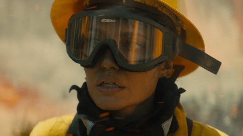 Angelia Jolie ca Hannah Faber arătând îngrijorată în timp ce poartă ochelari de protecție și echipament de protecție împotriva incendiilor în Those Who Wish Me Dead