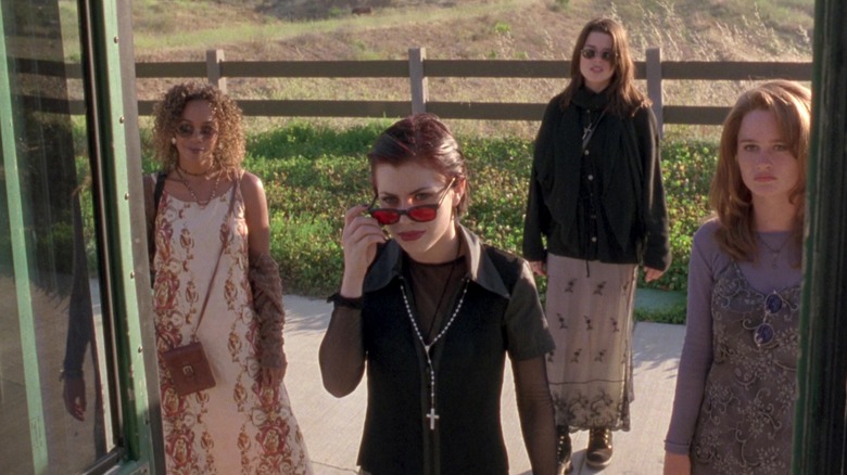 Rachel True ca Rochelle Zimmerman, Fairuza Balk ca Nancy Downs, Neve Campbell ca Bonnie Harper și Robin Tunney ca Sarah Bailey stând în jurul unui autobuz în The Craft