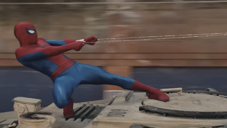 Omul Păianjen lăsat pe spate, agățat de două fire de chingă, în Spider-Man: Brand New Day