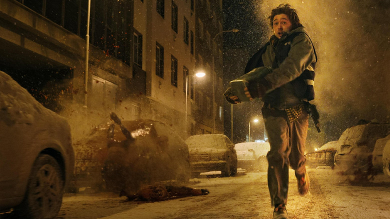 Austin Abrams ca Bryan alergând pe stradă în timp ce cadavrele explodează în jurul lui în Resident Evil (2026)