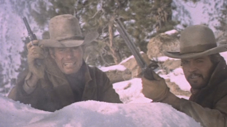 Will Penny al lui Charlton Heston și Blue al lui Lee Majors trag din spatele unor stânci din Will Penny