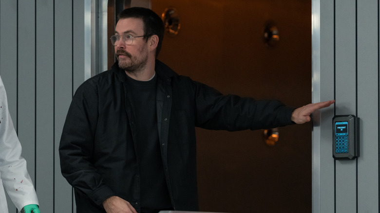 Regizorul Zach Cregger stă lângă un actor care poartă o halat de laborator stropit cu sânge pe platoul de filmare din Resident Evil