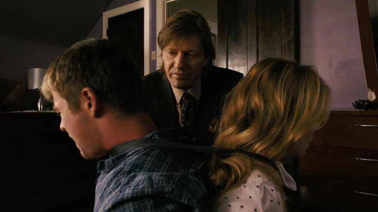 Sean Bean în rolul lui Pyke Kubic privindu-l pe Chris Hemsworth în rolul lui Sam și Victoria Profeta în rolul Leslie legat de un scaun în Ca$h