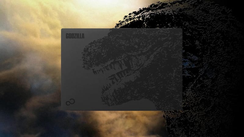 Capac pentru laptop Fujitsu Godzilla care arată o ilustrație Godzilla neagră și touchpad în formă de aripioară dorsală